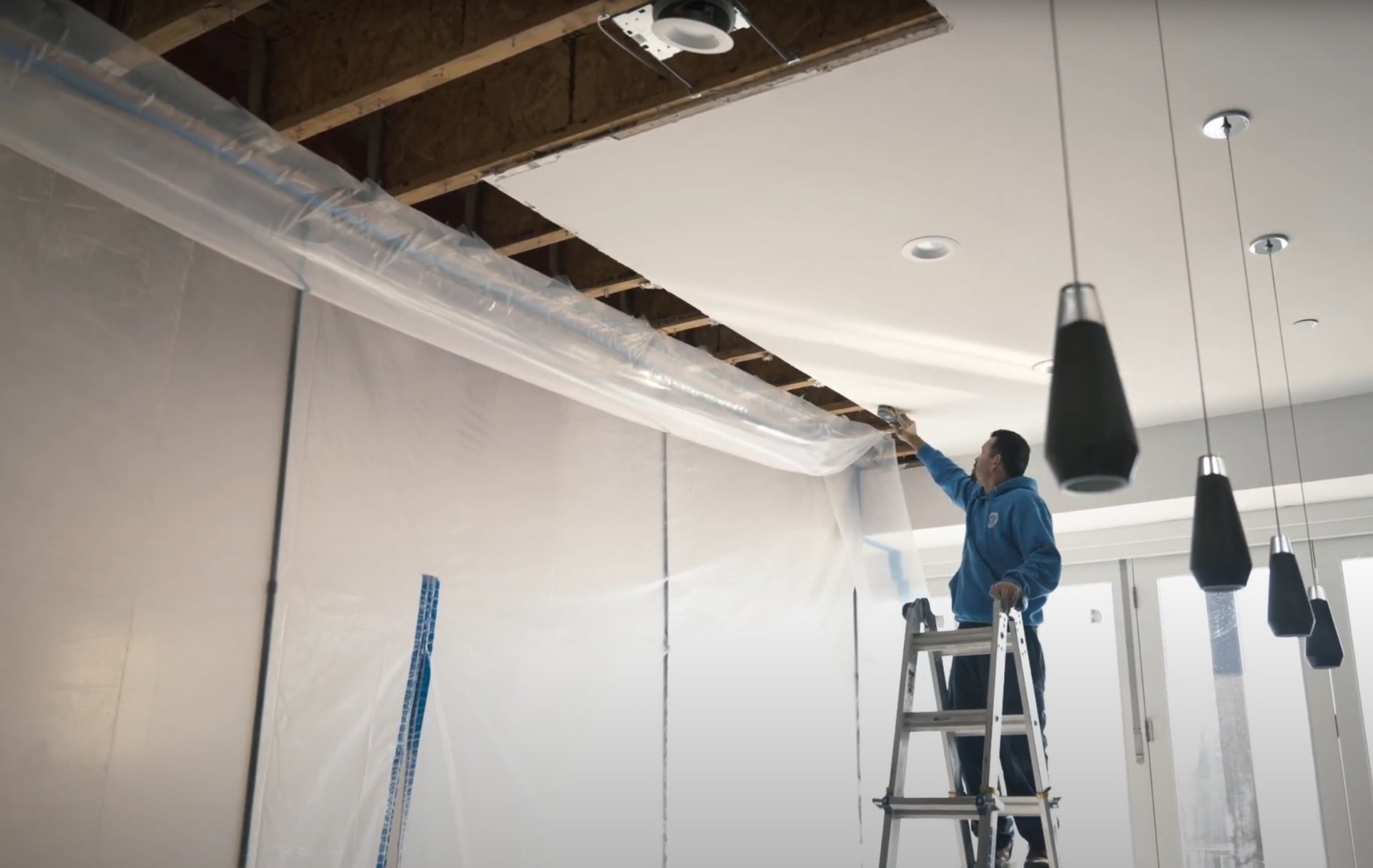 Professional ceiling water damage restoration in Katy, TX Water damage restoration professional working on ceiling repair with protective equipment